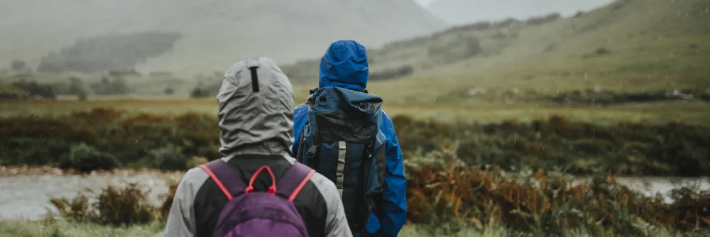 Paar in Regenjacken wandert bei Regen durch die Highlands
