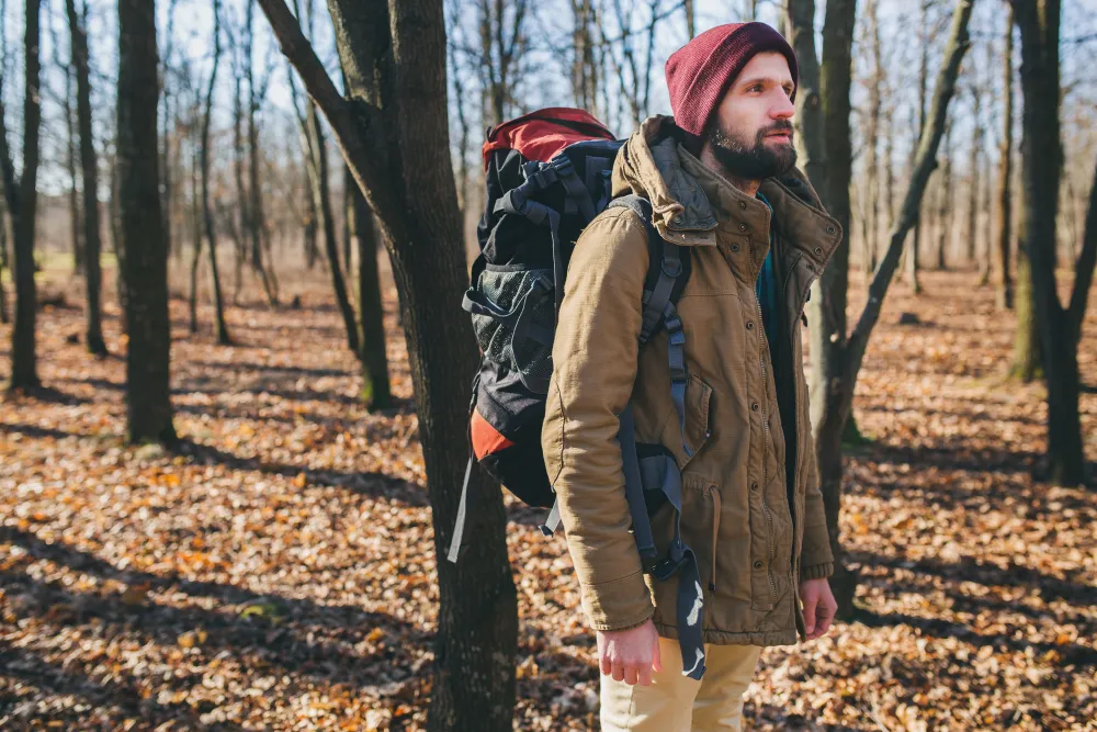 Wanderer mit Rucksack und warmer Jacke im Herbstwald