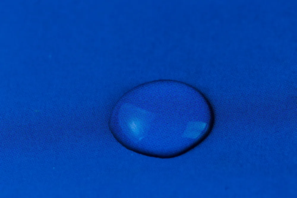 Wassertropfen perlen auf einem blauen Stoff ab